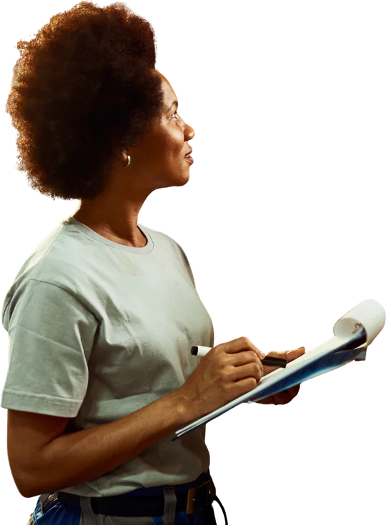 A warehouse worker writing an inventory list while checking stock.